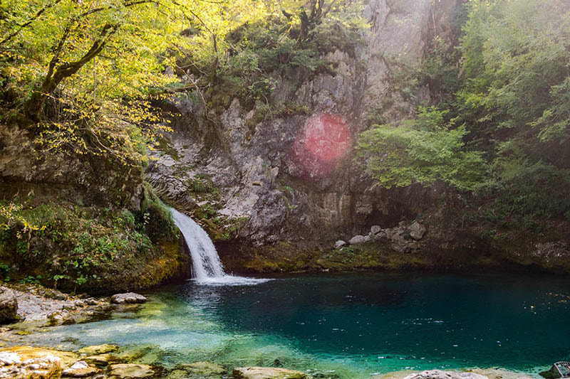 Photo of Blue Eye of Thethi, a beautiful waterfall in Albania with blue-green water. The perfect day trip from Shkodra Albania!