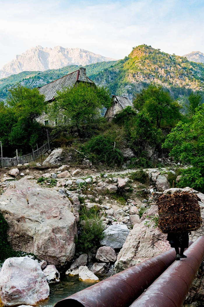 Beautiful photo of rural life in Albania showing a woman carrying sticks back to Theth. See more photos of how beautiful Albania is! #Travel #Albania #Balkans